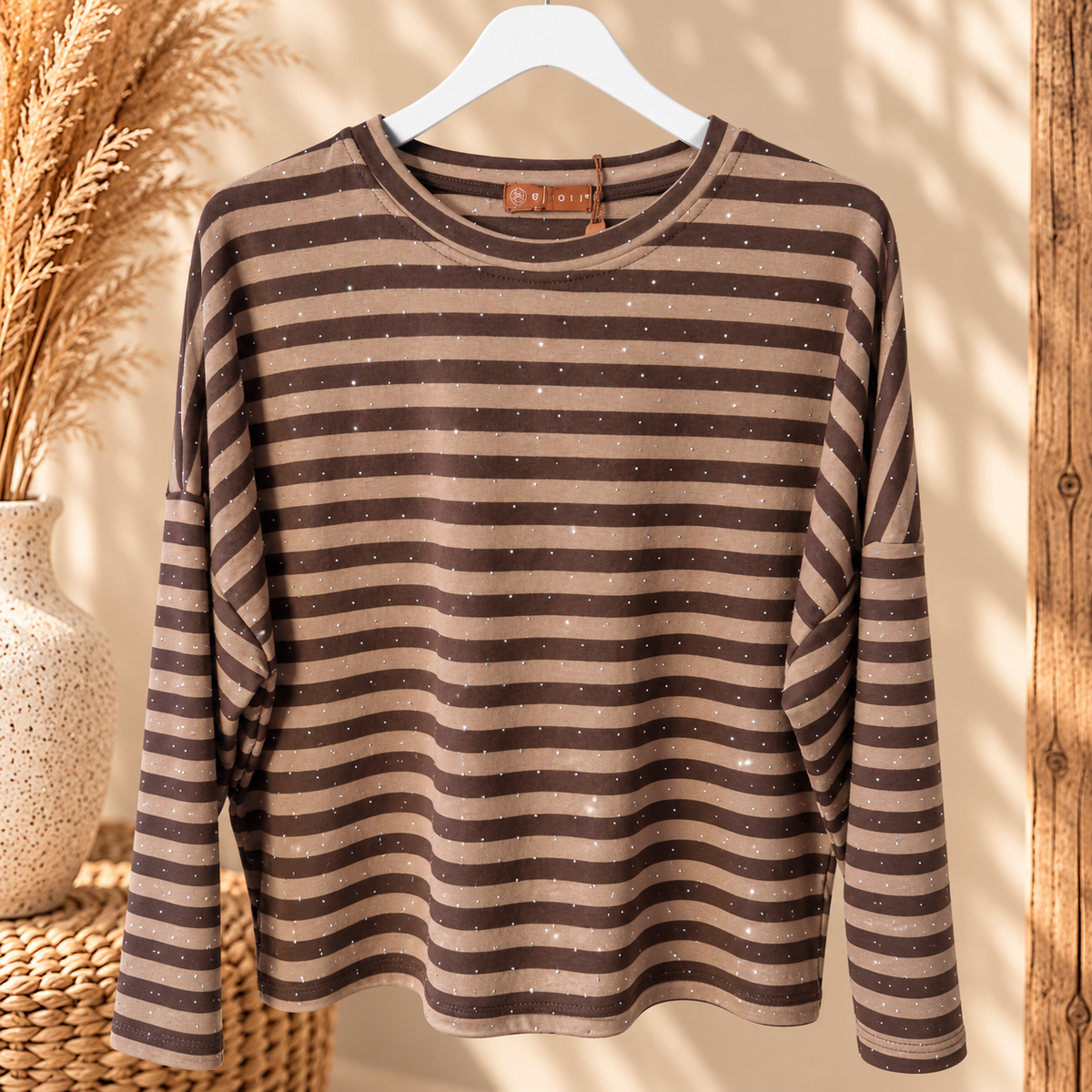 MOOI gestreepte top in taupe en donkerbruin met subtiele strasssteentjes en lange mouwen op een kledinghanger